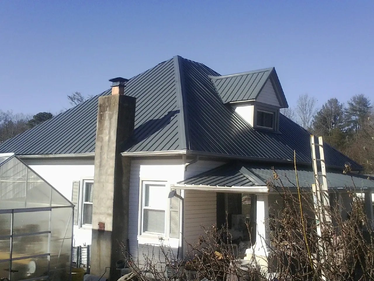 Dark blue standing seam metal roof on a white farmhouse with dormer — Slate & Tile Roof Repair by Roofing Brothers in Cokato