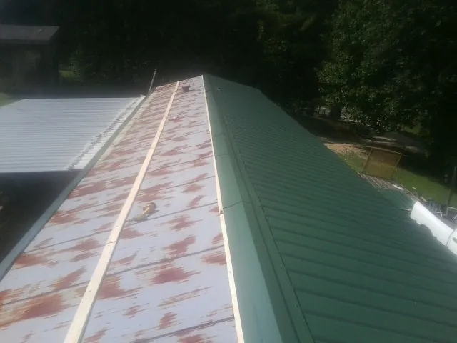 Old rusted panels beside newly installed green metal roofing — Wind Damage Roof Repair by Roofing Brothers in Cokato