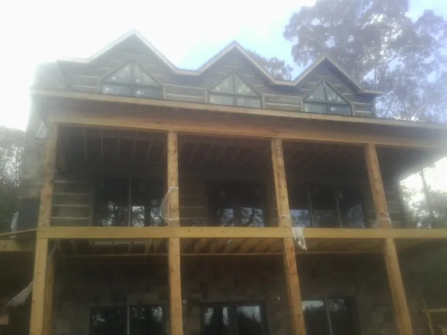 Dormers and porch framing on a large log home under construction — Roof Coating work by our crew in Cokato