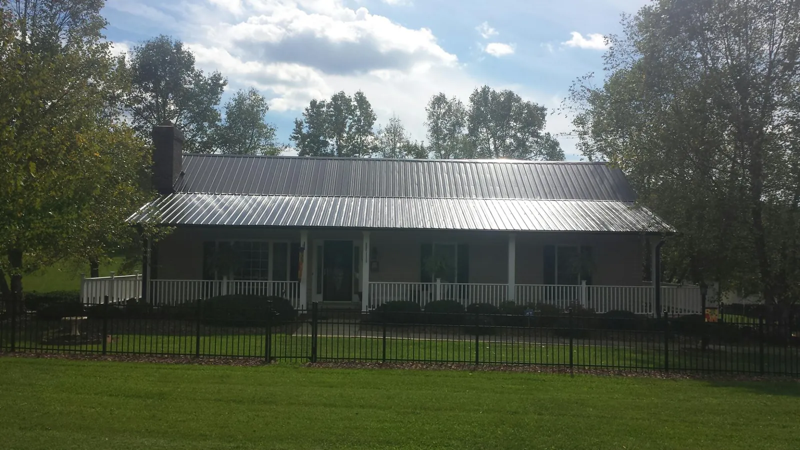 Gray metal roof on a brick ranch with a full width front porch — Gutter Guard Installation work by our crew in Cokato
