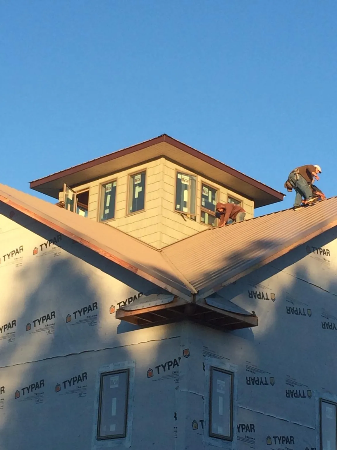 Roofers working around a rooftop cupola on a new metal roof at sunset — Roof Waterproofing in Cokato by Roofing Brothers